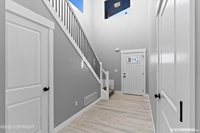 foyer entrance with a healthy amount of sunlight, light wood-type flooring, and a towering ceiling