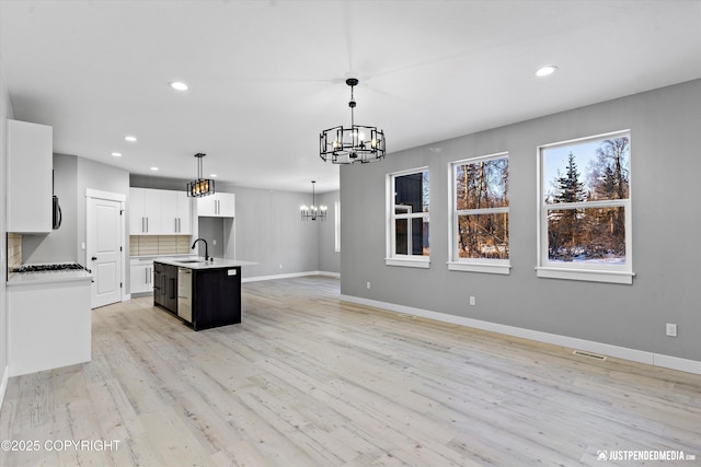 kitchen with white cabinets, pendant lighting, sink, and a kitchen island with sink