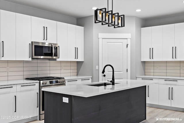 kitchen featuring sink, a center island with sink, white cabinets, and appliances with stainless steel finishes