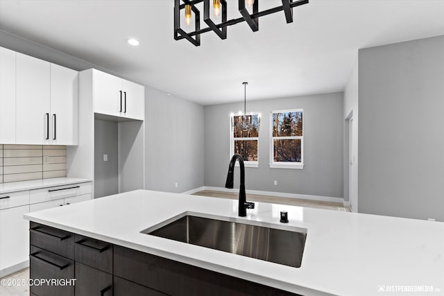 kitchen featuring sink, decorative backsplash, decorative light fixtures, white cabinetry, and a chandelier