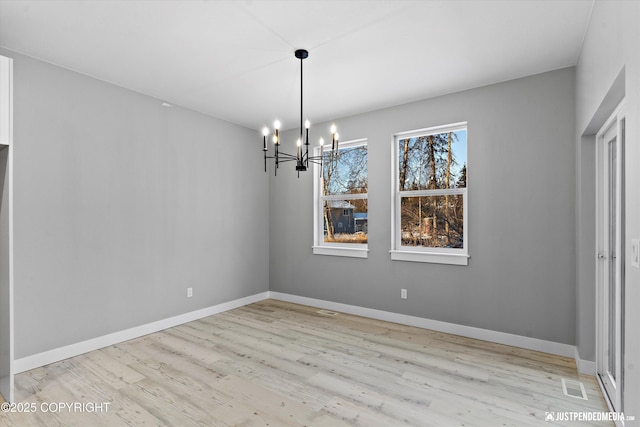 unfurnished dining area featuring a notable chandelier and light hardwood / wood-style flooring