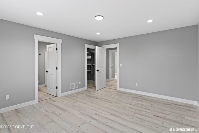 unfurnished bedroom featuring light hardwood / wood-style floors, a spacious closet, and a closet