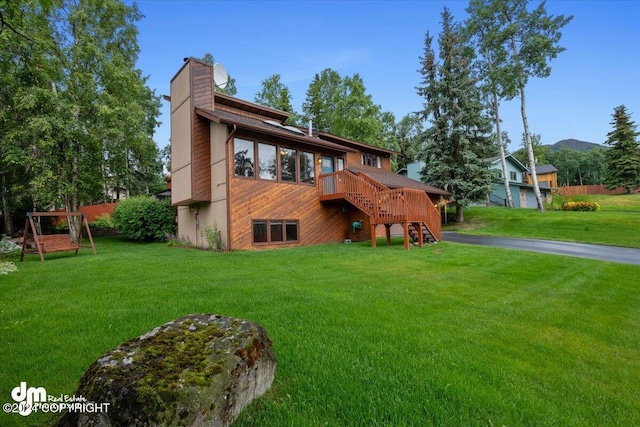 rear view of property featuring a wooden deck and a yard