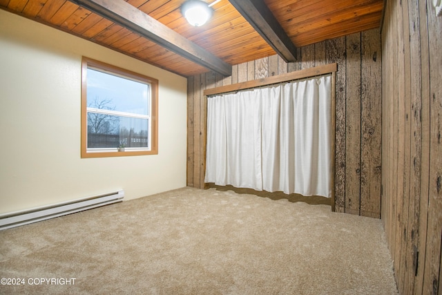 carpeted empty room featuring wood walls, beam ceiling, wood ceiling, and a baseboard heating unit