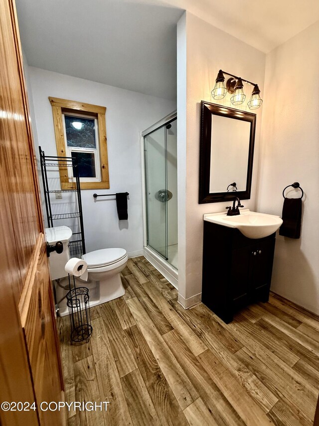 bathroom with hardwood / wood-style flooring, vanity, toilet, and a shower with shower door