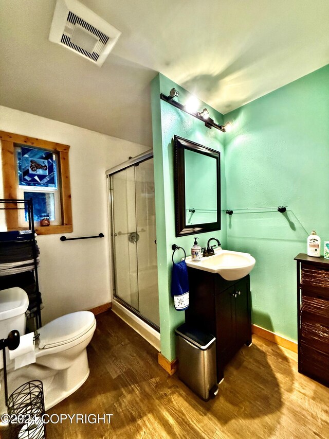 bathroom featuring wood-type flooring, vanity, toilet, and a shower with door