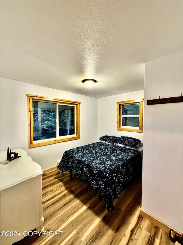 bedroom featuring light hardwood / wood-style floors and a textured ceiling