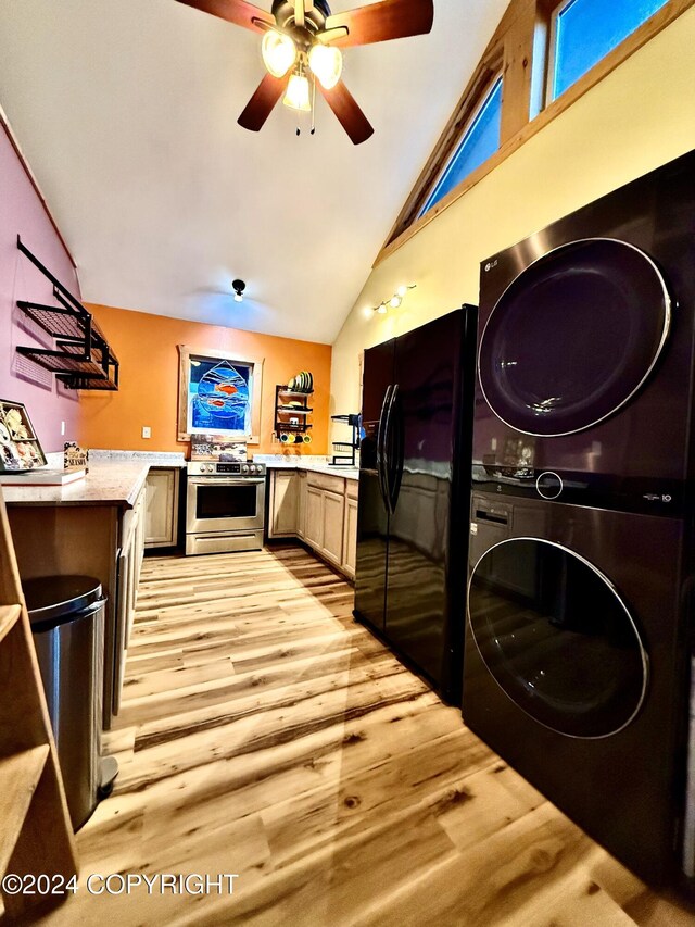 kitchen with black fridge, light hardwood / wood-style floors, lofted ceiling, stainless steel stove, and stacked washer and clothes dryer