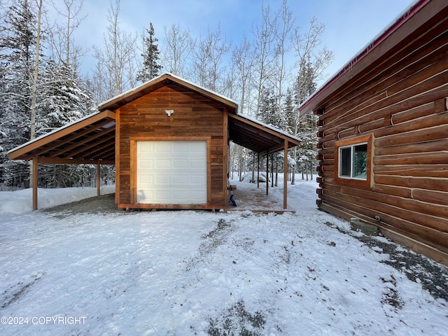 snow covered garage featuring a carport