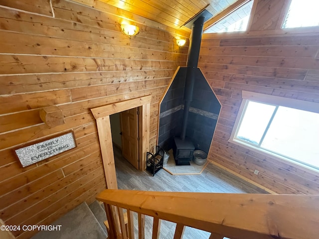 additional living space featuring wood-type flooring, a wood stove, lofted ceiling, and wood walls