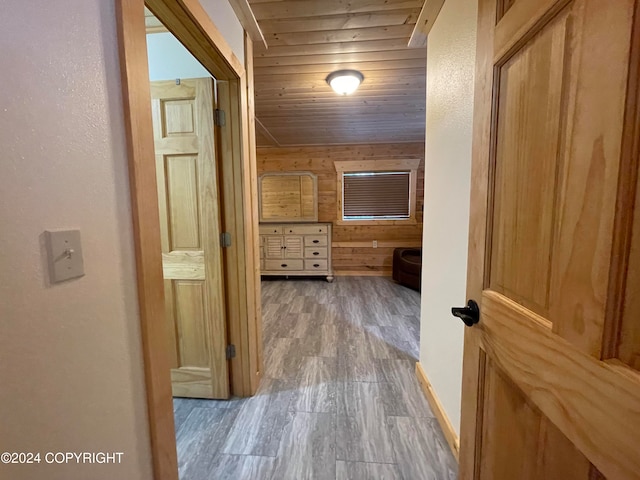 corridor featuring wood walls, wooden ceiling, and light wood-type flooring