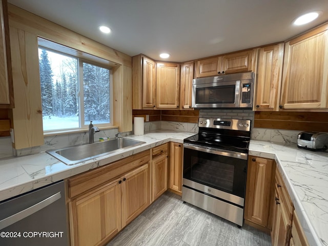 kitchen featuring backsplash, light wood-type flooring, sink, and appliances with stainless steel finishes