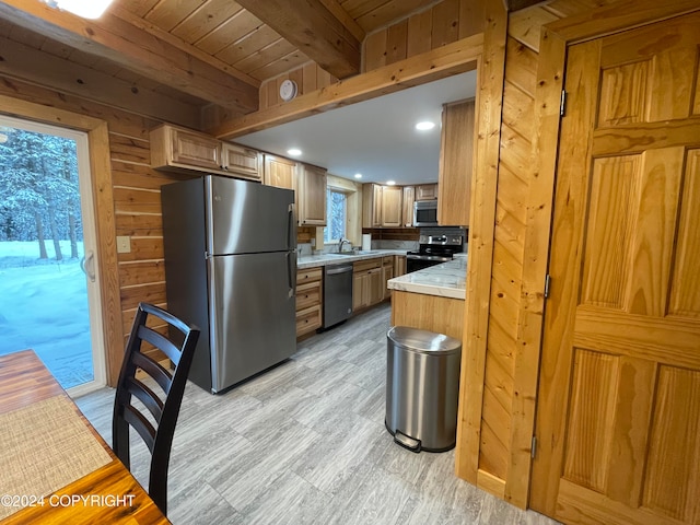 kitchen featuring wood walls, sink, light wood-type flooring, beam ceiling, and stainless steel appliances