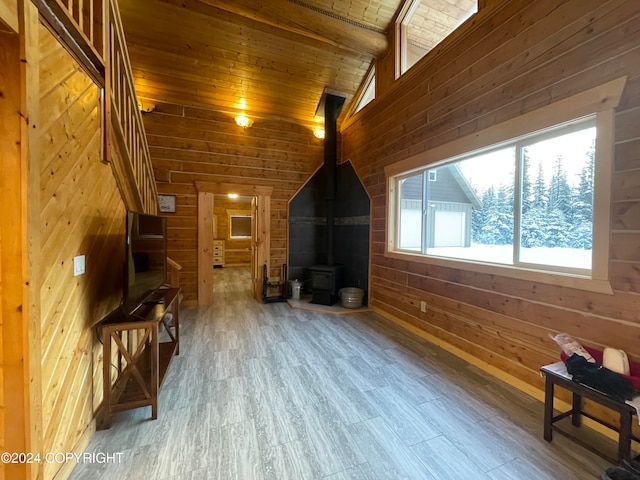 additional living space with a wood stove, wooden ceiling, vaulted ceiling with beams, wood walls, and hardwood / wood-style flooring