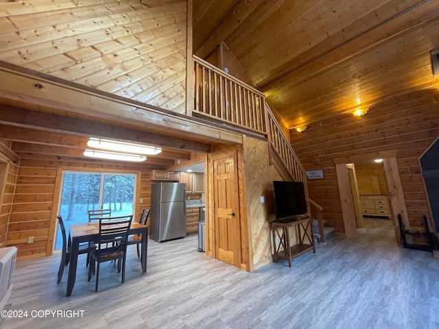 dining room with wood walls, light wood-type flooring, wood ceiling, and vaulted ceiling