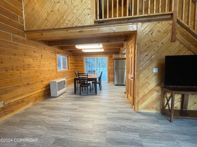 unfurnished dining area featuring beam ceiling and wooden walls