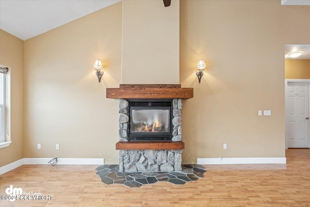 living room with a stone fireplace, light hardwood / wood-style floors, and vaulted ceiling