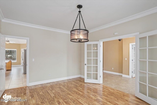 spare room with ceiling fan with notable chandelier, light wood-type flooring, crown molding, and french doors