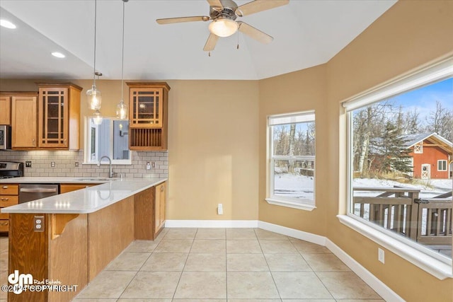 kitchen featuring kitchen peninsula, backsplash, stainless steel appliances, sink, and hanging light fixtures