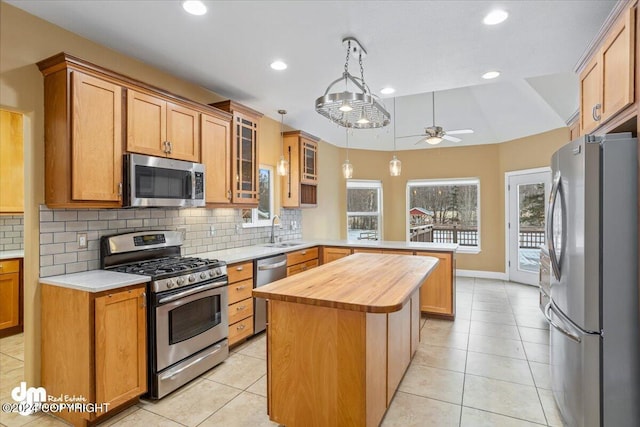 kitchen with stainless steel appliances, vaulted ceiling, ceiling fan, sink, and a center island