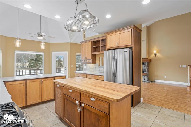 kitchen featuring stainless steel fridge, a kitchen island, light tile patterned floors, and ceiling fan