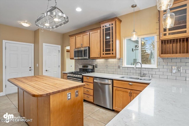 kitchen featuring sink, a center island, hanging light fixtures, stainless steel appliances, and light tile patterned floors