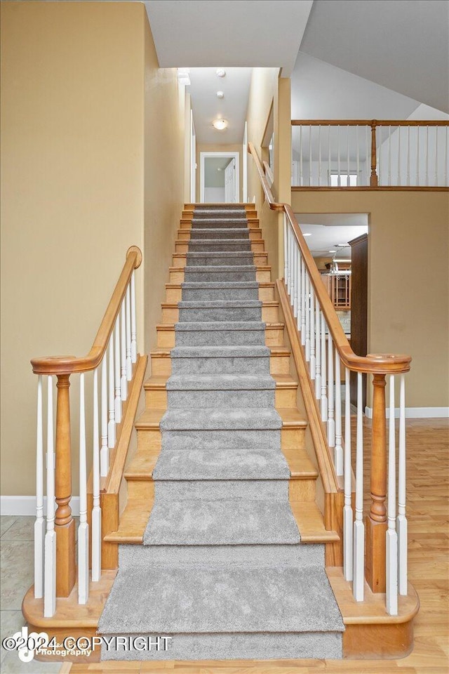 stairway featuring hardwood / wood-style floors and a high ceiling