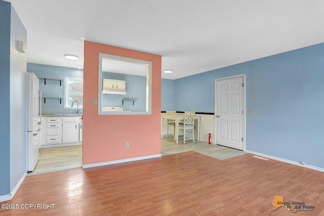 empty room featuring a sink, baseboards, and light wood-style floors