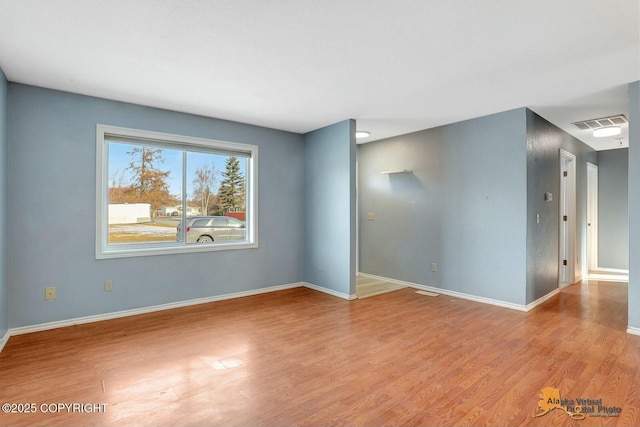 spare room with visible vents, baseboards, and wood finished floors