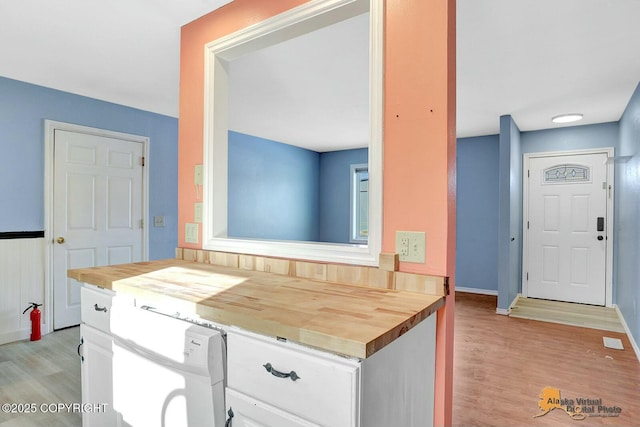 kitchen featuring dishwasher, light wood-style floors, butcher block countertops, and white cabinetry