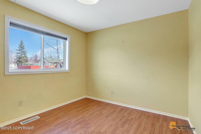 unfurnished room featuring wood finished floors, visible vents, and baseboards