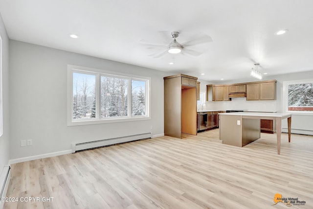 kitchen featuring a wealth of natural light, a baseboard radiator, decorative light fixtures, and light hardwood / wood-style floors