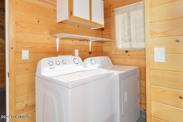 washroom featuring wooden walls, cabinets, and independent washer and dryer