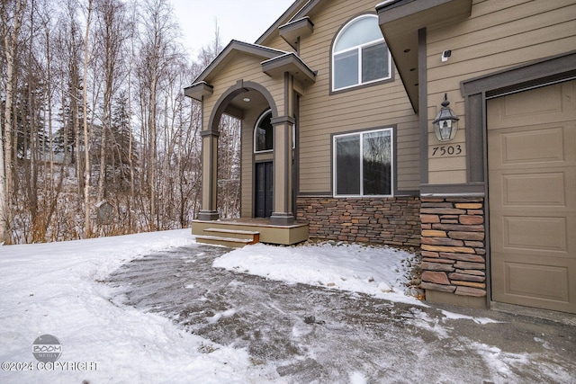 snow covered property entrance featuring a garage