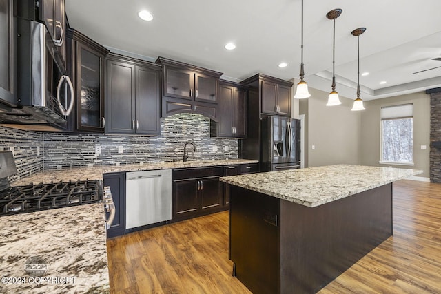 kitchen with hanging light fixtures, dark brown cabinets, a kitchen island, dark hardwood / wood-style flooring, and stainless steel appliances