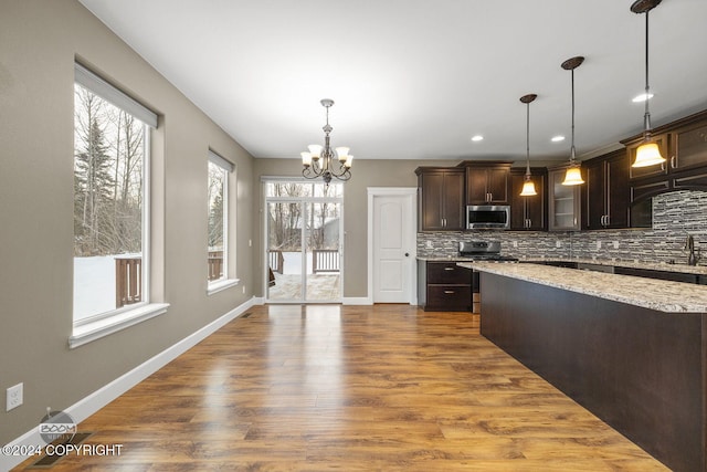 kitchen with hanging light fixtures, tasteful backsplash, a notable chandelier, dark brown cabinetry, and stainless steel appliances