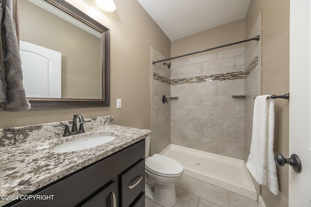 bathroom with tile patterned flooring, a tile shower, vanity, and toilet