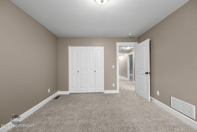 unfurnished bedroom featuring light carpet and a closet