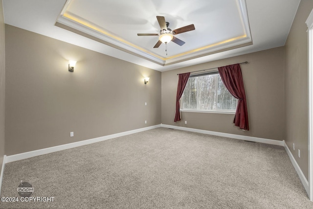 carpeted spare room featuring a raised ceiling and ceiling fan