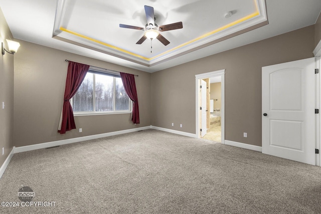 carpeted empty room with a tray ceiling and ceiling fan