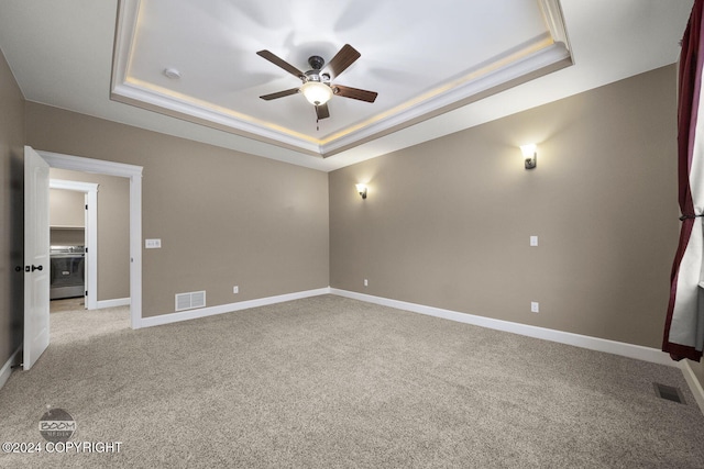 spare room featuring a tray ceiling, ceiling fan, and light colored carpet