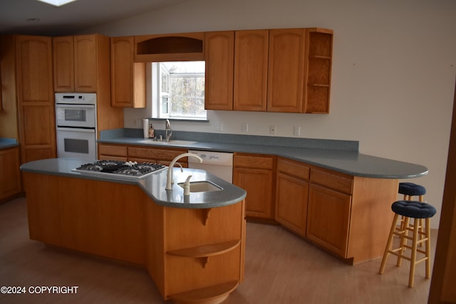 kitchen with light hardwood / wood-style flooring, an island with sink, white appliances, and sink