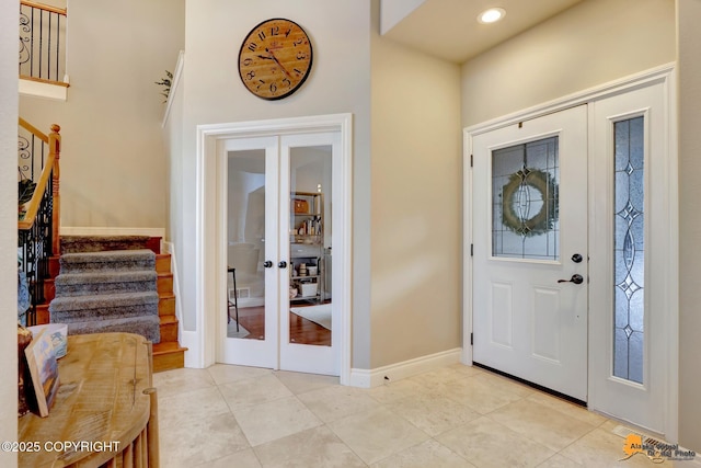 entryway with light tile patterned floors, baseboards, stairway, and french doors