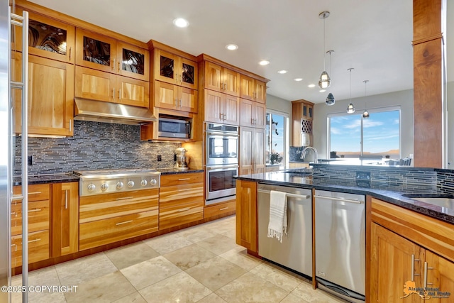 kitchen with pendant lighting, backsplash, appliances with stainless steel finishes, dark stone countertops, and under cabinet range hood