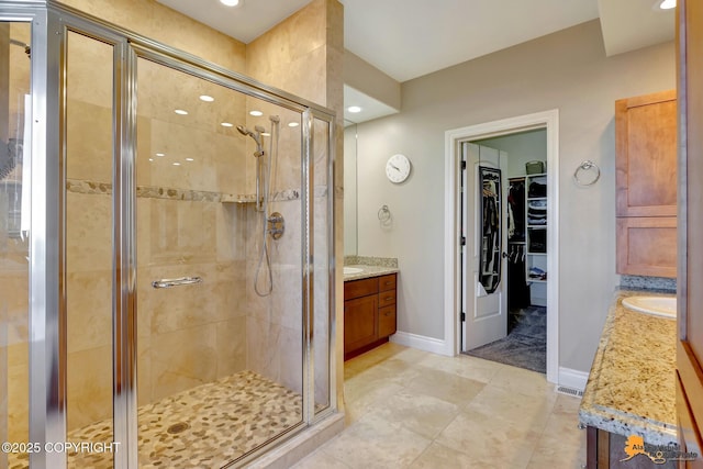 full bathroom featuring a walk in closet, visible vents, a stall shower, vanity, and baseboards