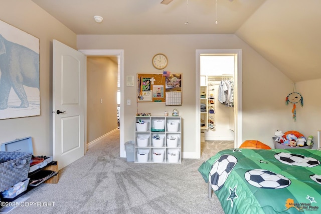 carpeted bedroom with a spacious closet, baseboards, and vaulted ceiling