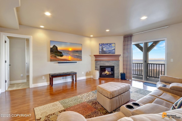 living room with recessed lighting, baseboards, wood finished floors, and a glass covered fireplace