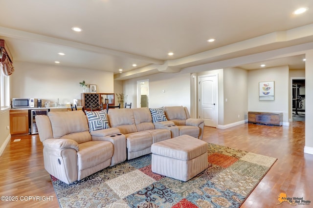 living area featuring light wood-style flooring, recessed lighting, beverage cooler, baseboards, and wet bar