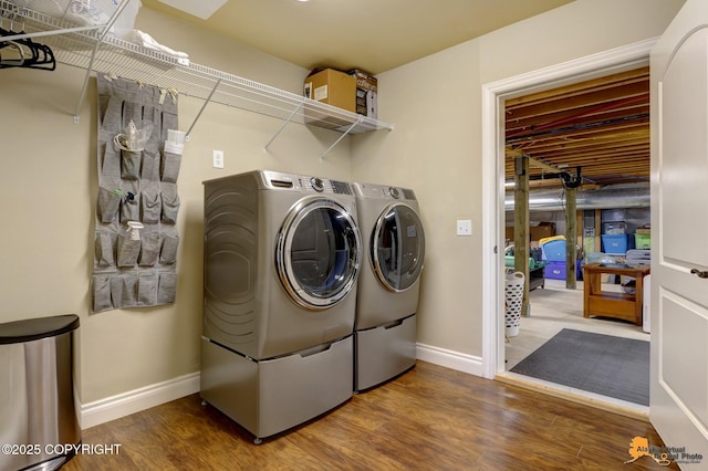 clothes washing area featuring laundry area, baseboards, wood finished floors, and washing machine and clothes dryer