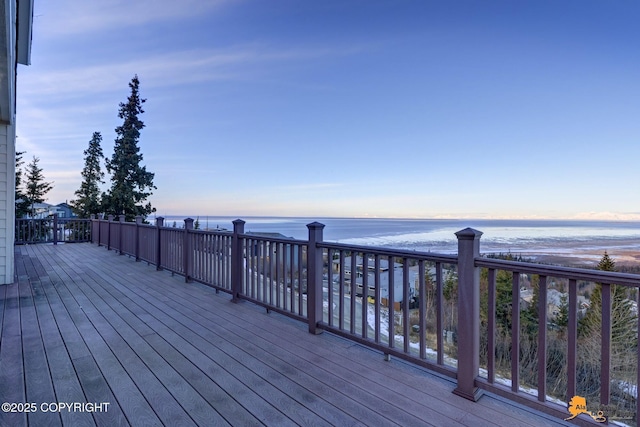 deck at dusk featuring a water view